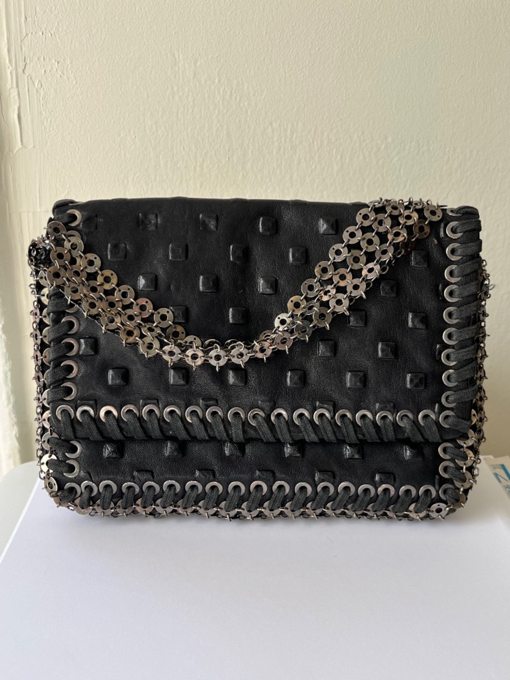 Black bag with a chain handle and metal detailing. Size 7,0x5,5 in